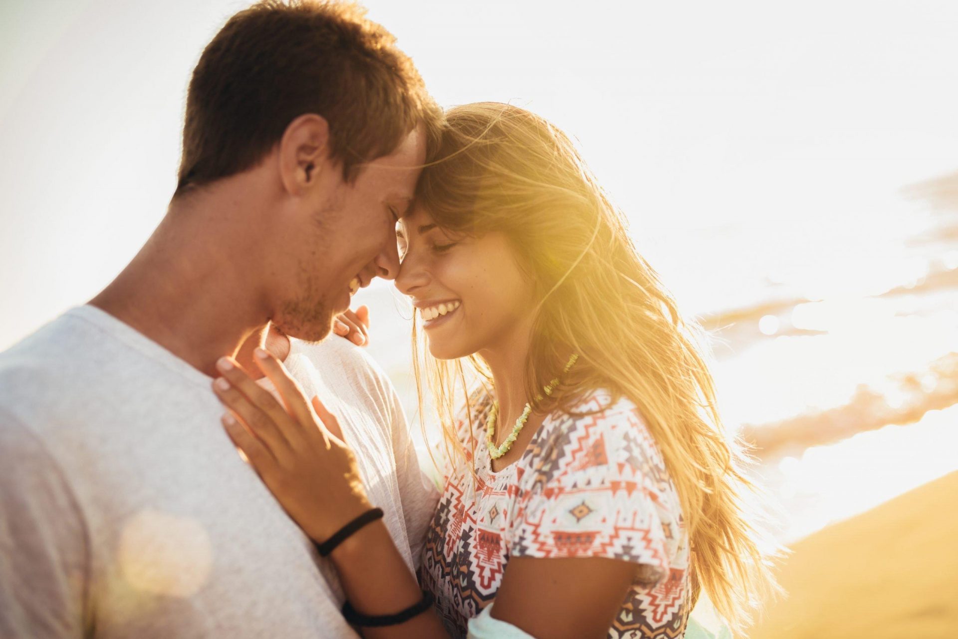 Romantic couple on the beach at colorful sunset.