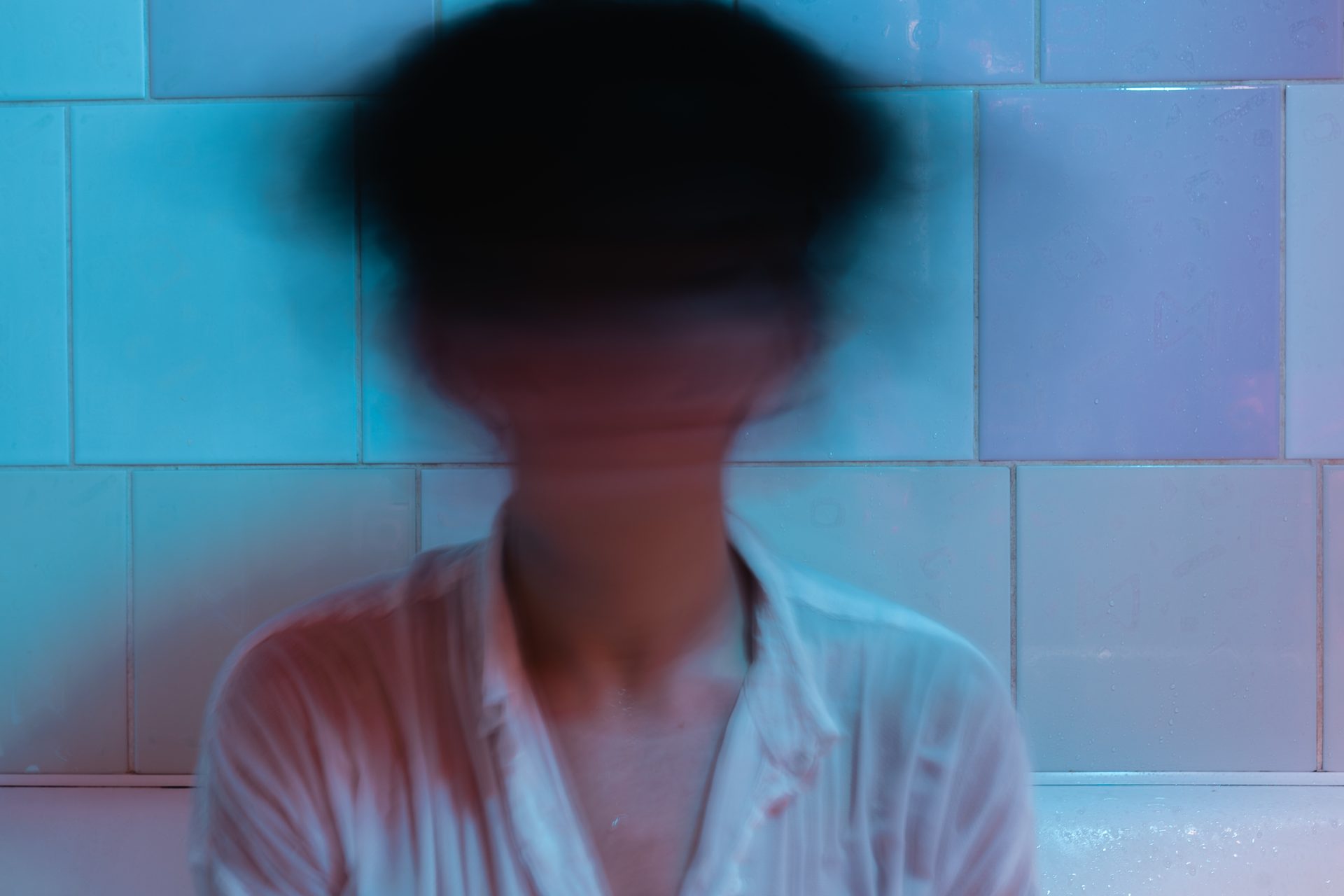 a blurry face with dark hair. The face is blurry because it appears to be a person shaking their head rapidly.
