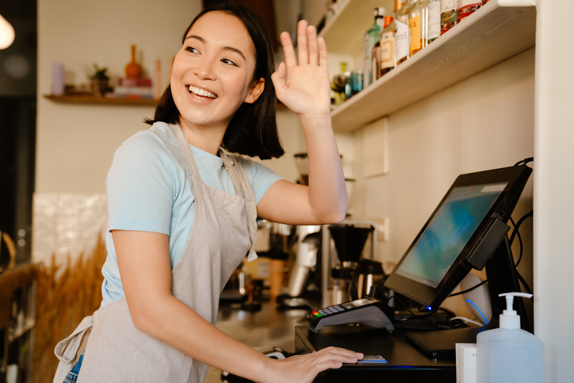 Asian barista woman gesturing while working with cash register