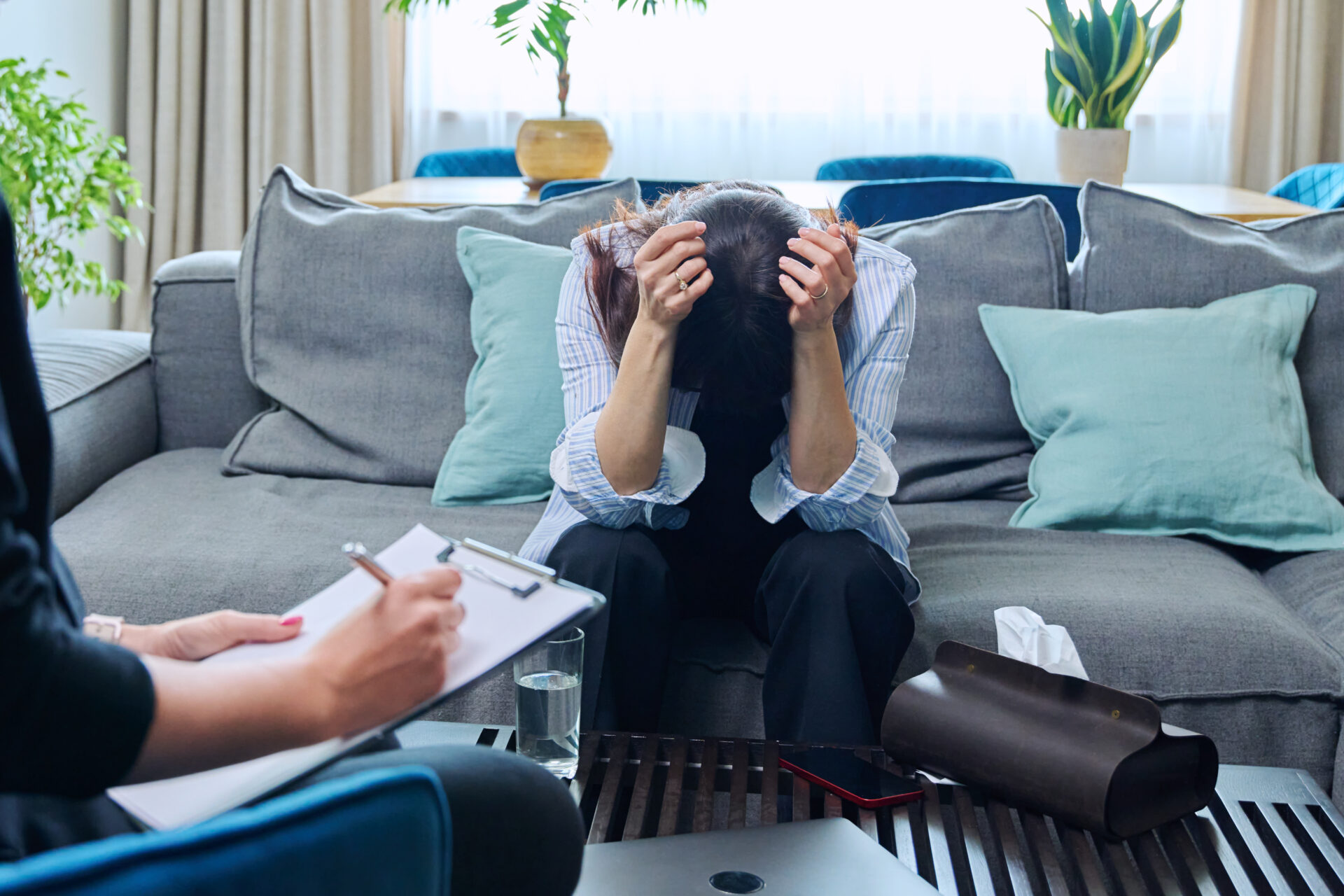Sad crying middle-aged woman sitting on couch in therapy with psychologist