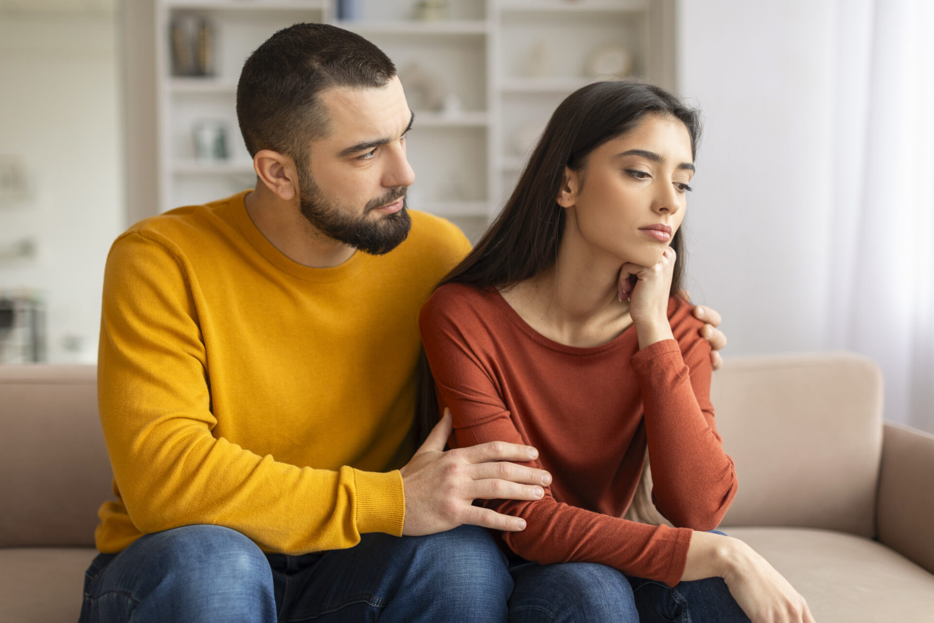 Compassionate young man comforting his upset wife at home